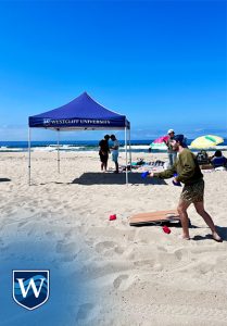 Westcliff University Student Life beach day, Huntington Beach. Students playing cornhole