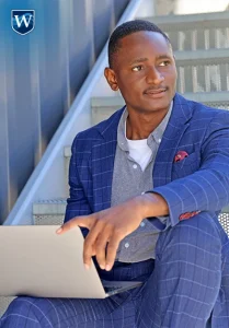 Tim Udoma., Westcliff University, studying on laptop in stairwell